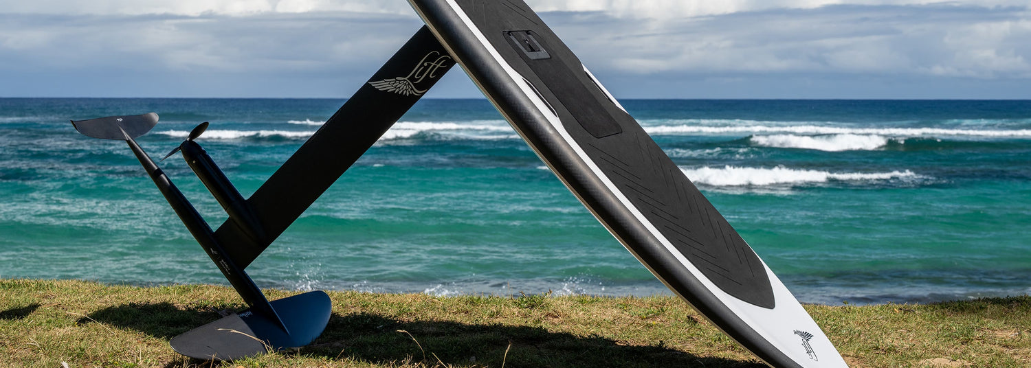 Lift eFoil board and hydrofoil propped on a grassy shoreline by the sea