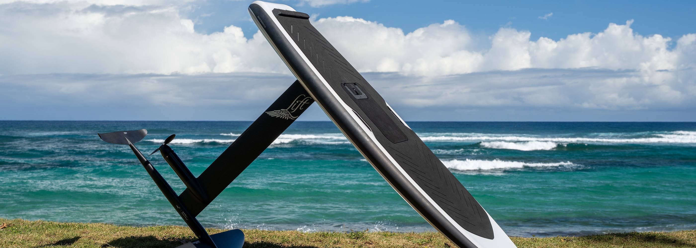 Lift eFoil board and carbon hydrofoil standing on the grass beside the ocean